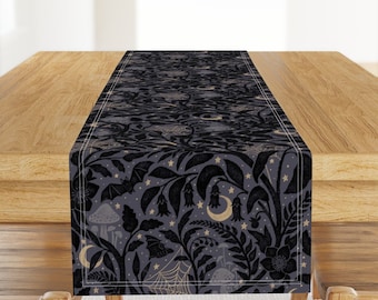 May include: A black and gold table runner with a spooky forest design. The pattern features bats, mushrooms, crescent moons, and stars on a dark gray background.