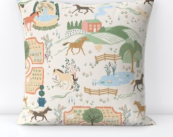 May include: A cream-colored throw pillow with a repeating pattern of horses, houses, trees, and ponds. The pattern is in shades of brown, green, blue, and pink.