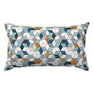 Könnte beinhalten: Ein rechteckiges Kissen mit einem geometrischen Muster aus türkisfarbenen, blauen, weißen und goldenen Quadraten. Das Kissen ist aus einem weichen, strukturierten Stoff gefertigt.