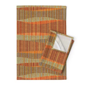 May include: Two kitchen towels with a geometric pattern in shades of orange, brown, and green. The towels are folded and displayed on a white background.