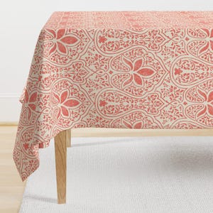 May include: A coral pink and cream tablecloth with a damask pattern. The tablecloth is made of a soft, woven fabric and has a subtle sheen.