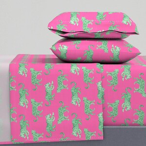 May include: Pink bed sheet set with a green leopard print. The set includes a flat sheet, fitted sheet, and two pillowcases.