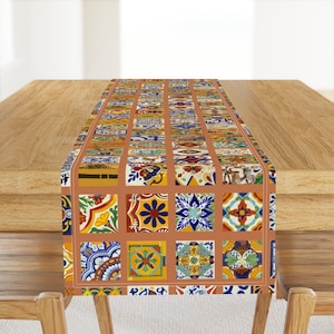 May include: A brown table runner with a colourful tile pattern. The tiles are in various shades of blue, green, yellow, red, and orange. The runner is 35.5 cm wide and 177.8 cm long.