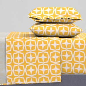 May include: A yellow and white geometric patterned bed sheet set with two matching pillowcases. The pattern features white stars within yellow squares.