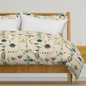 Pode incluir: Uma capa de edredom bege com um padrão geométrico de pássaros, círculos e quadrados em tons de azul, verde, amarelo e vermelho.