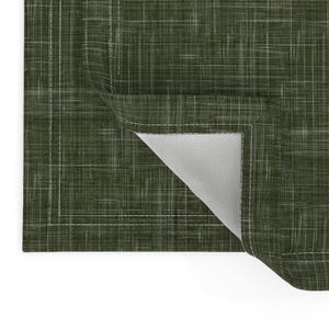 May include: A green placemat with a subtle woven texture and a white stitched border. The placemat is folded to show the white underside.