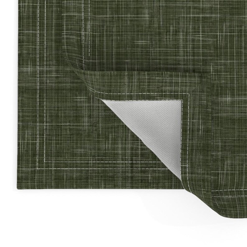 May include: A green placemat with a subtle woven texture and a white stitched border. The placemat is folded to show the white underside.