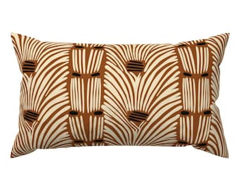 Puede incluir: Una almohada rectangular marrón y crema con un patrón geométrico. El patrón presenta una serie de líneas verticales con círculos negros y un diseño curvo.