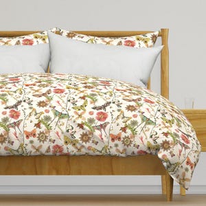 May include: A white duvet cover with a floral and butterfly pattern. The duvet cover features a variety of butterflies in shades of pink, yellow, orange, and green. The background is a cream color with a subtle floral pattern.