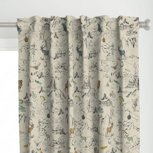 Può includere: Tenda beige con una dettagliata illustrazione di una scena di montagna. Il design include cervi, baite, biciclette, parapendio e altri elementi esterni in nero, blu e giallo. La tenda è appesa a un'asta bianca.