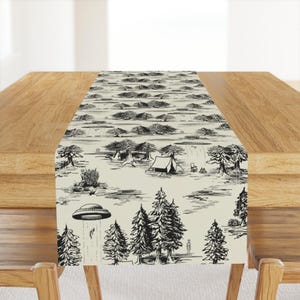 May include: A rectangular table runner featuring a repeating black and white ink-style illustration of a forest landscape. The design depicts pine trees, a camping tent, and multiple flying saucers hovering above the ground with light beams.