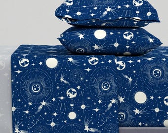 May include: A blue and white bedding set with a celestial pattern featuring stars, moons, and planets. The set includes a flat sheet, fitted sheet, and two pillowcases.