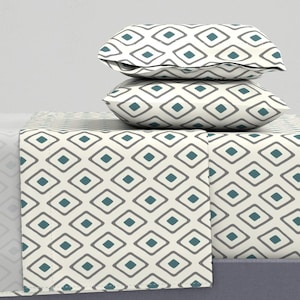 May include: A white and teal geometric patterned bedding set with two pillowcases and a flat sheet.