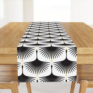 May include: Black and white table runner with a repeating pattern of stylized black cranes with gold beaks and legs on a white background.