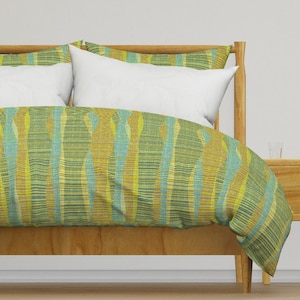 May include: A green and yellow patterned duvet cover with a white pillow on a wooden bed frame.
