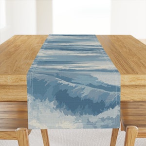 May include: A blue and white table runner with a wave pattern. The runner is made of a soft, woven fabric and has a subtle sheen.