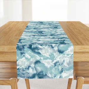 May include: A blue and white abstract marble pattern table runner. The runner has a light blue background with darker blue and white swirls.