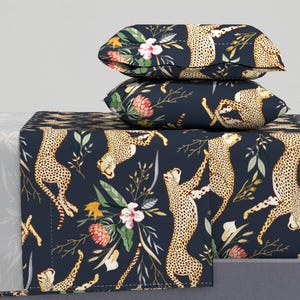 May include: A navy blue bedding set with a cheetah and floral print. The set includes a flat sheet, fitted sheet, and two pillowcases.