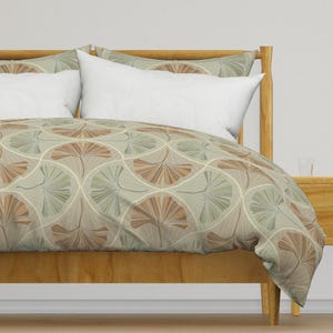 May include: A wooden bed frame with a light brown duvet cover featuring a repeating pattern of stylized ginkgo leaves in shades of green, brown, and beige.