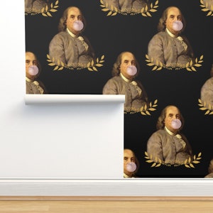 May include: A black and gold wallpaper pattern featuring a repeating image of Benjamin Franklin blowing a bubble. The image is set against a black background with gold leaf accents.