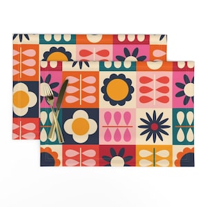 May include: Set of two colorful placemats with a geometric pattern of flowers, leaves, and circles in shades of red, orange, yellow, pink, blue, and green.