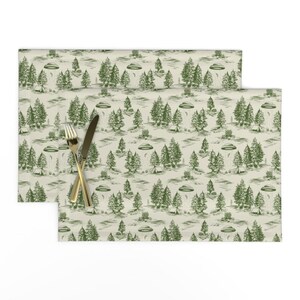 May include: A green and white table runner with a repeating pattern of trees and flying saucers. The pattern is reminiscent of a vintage illustration.