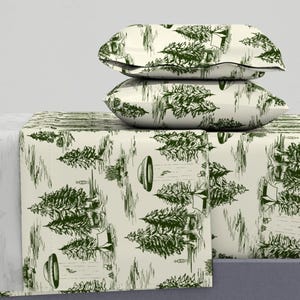 May include: A white and green bedding set with a woodland pattern featuring trees, tents, and flying saucers. The set includes a fitted sheet, flat sheet, and two pillowcases.