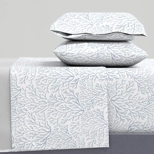 May include: A white and blue bedding set with a coral reef pattern. The set includes a flat sheet, fitted sheet, and two pillowcases.