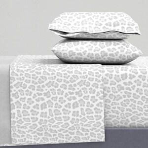 Könnte beinhalten: Ein weißes Bettwäsche-Set mit einem grauen Leopardenmuster. Das Set enthält ein Spannbettlaken, ein flaches Laken und zwei Kissenbezüge.