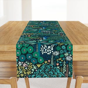 May include: A green and blue table runner with a floral pattern. The pattern features stylized trees, flowers, and leaves. The runner is perfect for adding a touch of nature to your dining table.