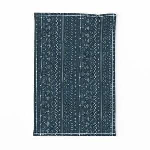 May include: A teal blue kitchen towel with a white geometric pattern. The pattern is made up of various shapes, including triangles, squares, and lines.