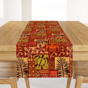 May include: A colorful table runner with a geometric pattern featuring a turtle, palm trees, and waves. The runner is made of a woven fabric and has a red, orange, yellow, and green color scheme.