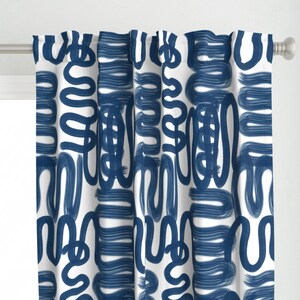 Puede incluir: Panel de cortina blanco con un patrón repetitivo de pinceladas azul marino. El diseño abstracto presenta líneas y formas gruesas y curvas, creando un aspecto moderno y artístico. La cortina está colgada de una barra plateada.