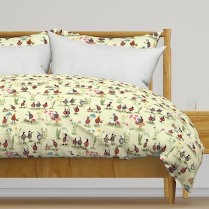 May include: A duvet cover and two pillowcases featuring a light yellow background with a repeating pattern of red ladybugs engaged in various activities, including walking, holding umbrellas, and pushing strollers among small flowers and mushrooms.