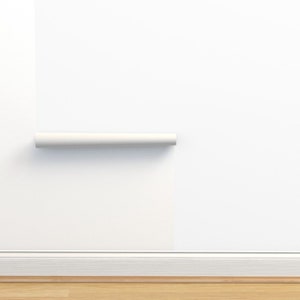 May include: A white wall with a white baseboard and a white roll of wallpaper hanging on the wall.