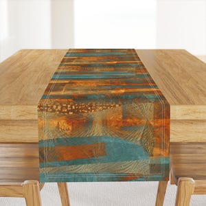 May include: A rectangular table runner with a distressed, abstract design. The runner features a mix of teal, orange, and brown hues, with a textured appearance. The design includes horizontal stripes and geometric patterns, adding visual interest to the table setting.
