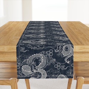 May include: A navy blue table runner with a white dragon design. The dragon is depicted in a traditional Japanese style, with swirling clouds and intricate details. The runner is made of a soft, textured fabric.