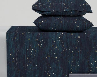 May include: A dark blue and teal bedding set with a gold star pattern. The set includes a flat sheet, fitted sheet, and two pillowcases.
