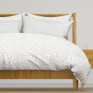 May include: A white duvet cover with a gray leopard print pattern on a wooden bed frame.