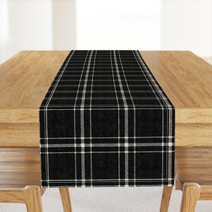 May include: Black and white plaid table runner. The runner has a woven texture and a classic plaid pattern.