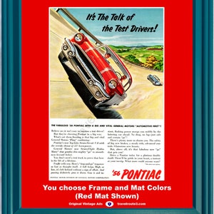 Op de afbeelding: Ingelijste vintage advertentie voor een rode '56 Pontiac auto, tegen een schilderachtige achtergrond. De advertentie bevat de tekst "It's The Talk of the Test Drivers!" en extra tekst. Het frame is teal.