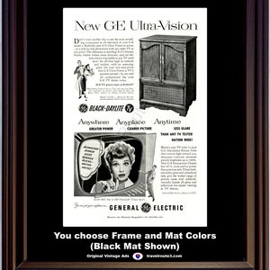 May include: Framed vintage advertisement for a General Electric Ultra-Vision TV. The ad features a black and white image of a television set and a woman watching TV. The frame is dark brown, and the mat is black.
