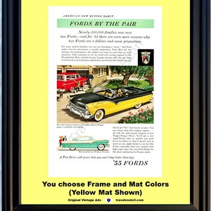 May include: Framed vintage advertisement for '55 Fords, featuring a black and yellow convertible and a red car. The ad includes text about Fords by the pair and mentions the '55 Ford models. The frame is black with a yellow mat.