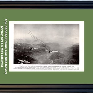 May include: Framed vintage black and white print featuring several airplanes flying over a mountainous landscape. The print is set against an army green mat and framed in a black frame. Text on the print reads "Flying Fortresses' Roar Shakes the Brenner Pass—Once the World Troubled when Axis Dictators Whispered Here."