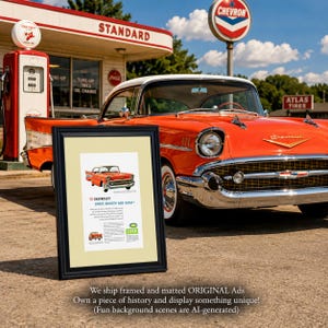 May include: A black framed print featuring a vintage 1957 Chevrolet advertisement with the text '57 CHEVROLET! SWEET, SMOOTH AND SASSY!' displayed in front of a full-sized orange 1957 Chevrolet car parked at a retro gas station with a Chevron sign.