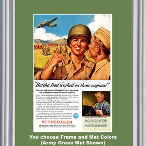 Peut inclure: Publicité vintage encadrée pour Studebaker, avec un soldat souriant. Le texte inclut "Betcha Dad worked on those engines!" et met en avant les moteurs Cyclone. Le cadre est blanc avec un passe-partout vert armée.