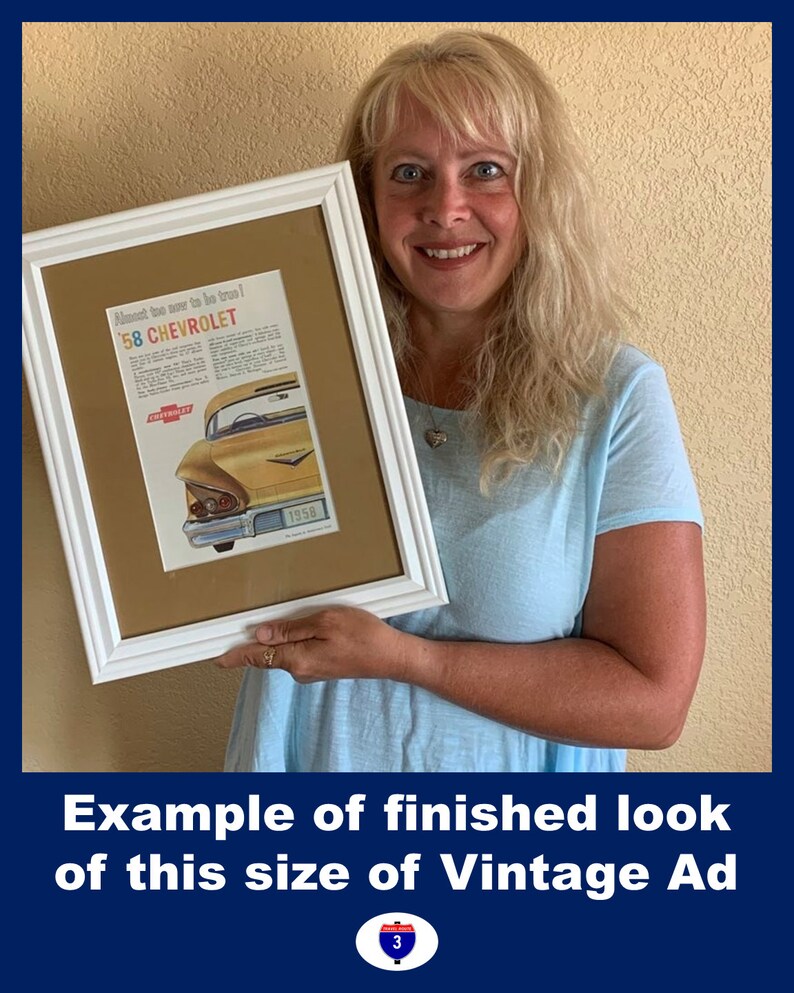 May include: A framed vintage advertisement for a 1958 Chevrolet car. The ad features a yellow car with red and white text. The frame is white, and the matting is tan. The image is held by a person.