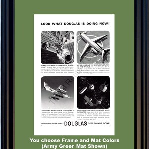 Puede incluir: Anuncio vintage enmarcado con un passe-partout verde militar. El anuncio presenta imágenes de aviones y naves espaciales con el texto "LOOK WHAT DOUGLAS IS DOING NOW!" y "DOUGLAS GETS THINGS DONE!"
