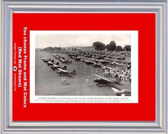 Könnte beinhalten: Ein gerahmtes Schwarz-Weiß-Foto einer großen Gruppe kleiner Propellerflugzeuge, die auf einem Flugfeld geparkt sind. Der Druck enthält Text unter dem Bild und ist in ein leuchtend rotes Passepartout und einen silbernen Rahmen gefasst. Der Text links lautet: You choose Frame and Mat Colors (Red Mat Shown).