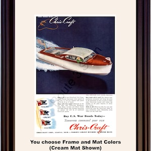 Op de afbeelding: Ingelijste vintage advertentie voor Chris-Craft motorboten. De afbeelding toont een speedboot met een witte romp, rode houten accenten en een kleine Amerikaanse vlag. De advertentie bevat tekst ter promotie van Amerikaanse oorlogsobligaties.